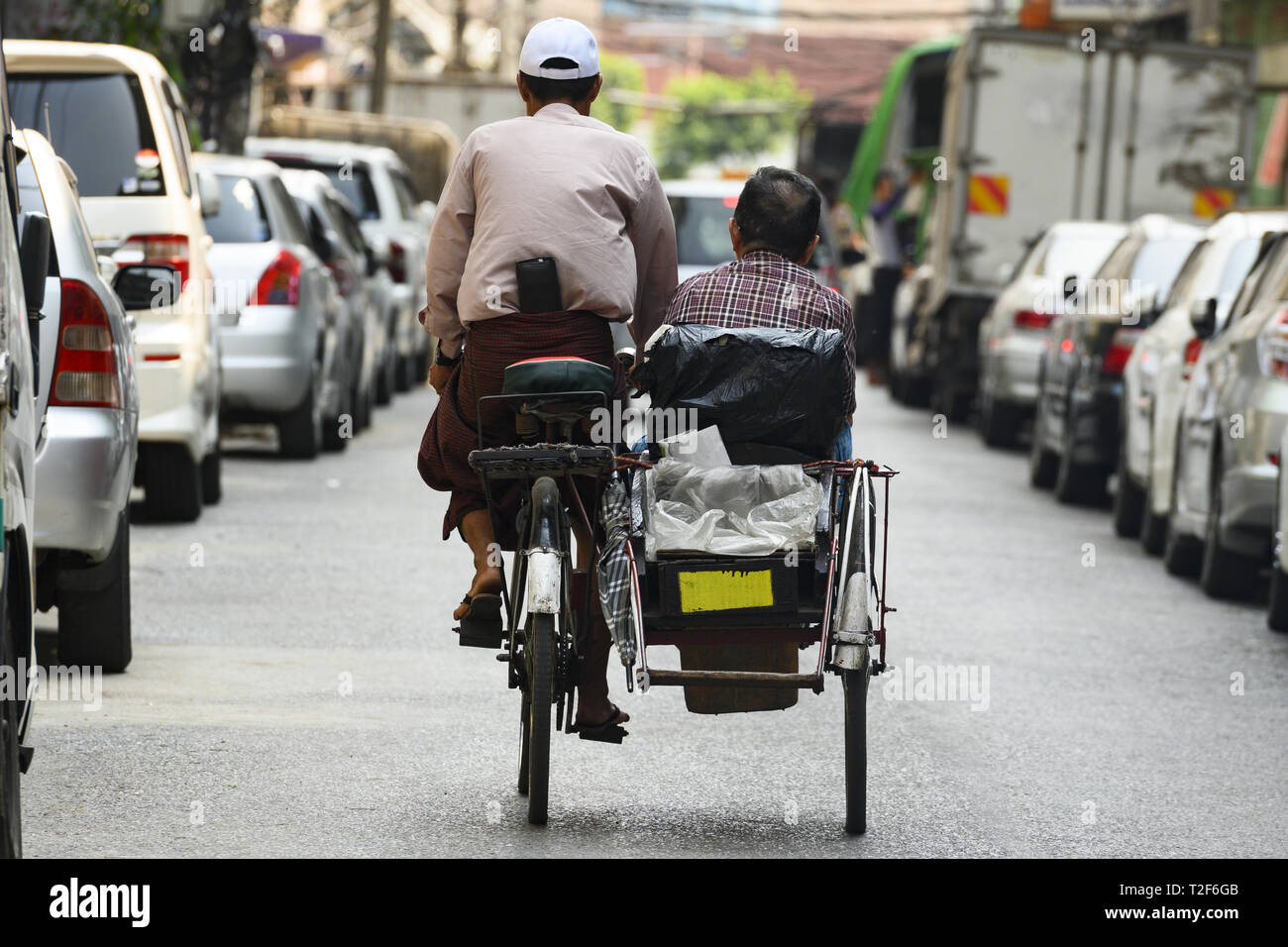 A unidentified Sai Kaa driver is carrying a passenger on his side car among the narrow streets of Yangon, Myanmar. Stock Photo