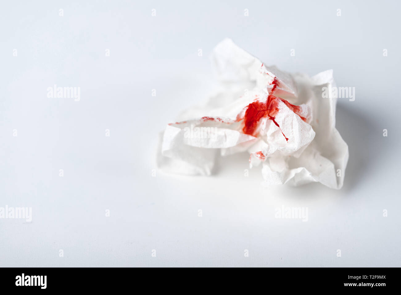 A photo of used bloody toilet paper on the light blue background. Menstrual or hemorrhoids bleeding Stock Photo