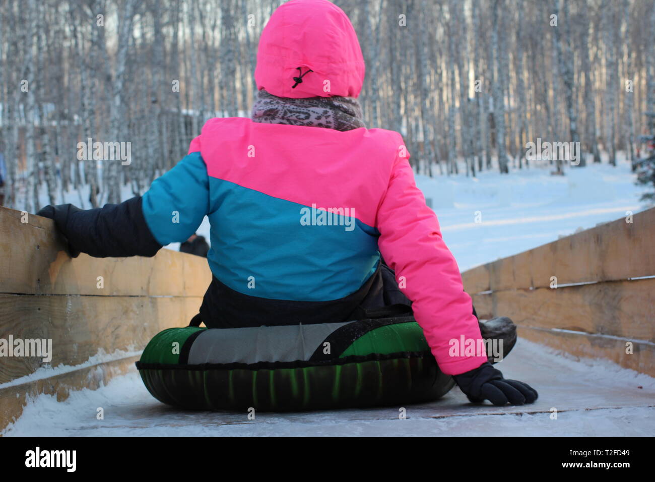 the girl prepared to roll down the ice slide in the winter on an inflatable sled Stock Photo