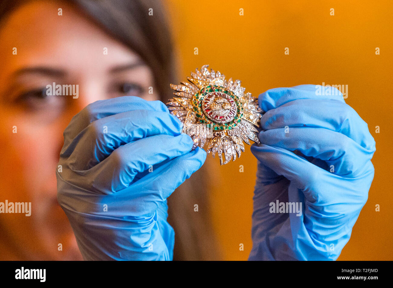 London, UK.  2 April 2019. A curator poses with Queen Victoria's Star and Collar of the Order of the Bath. Preview of "Queen Victoria's Palace" exhibition at Buckingham Palace.  The special exhibition marks the 200th anniversary of the birth of Queen Victoria (1819-1901) and tell the story of her 62 year reign and her life at Buckingham Palace.  Over 80 objects will be displayed as part of the Summer Opening of the State Rooms 20 July to 29 September 2019.  Credit: Stephen Chung / Alamy Live News Stock Photo