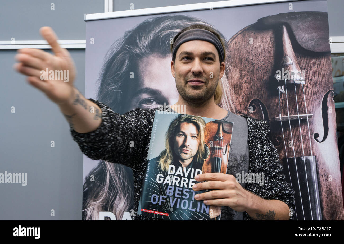 02 April 2019, Hessen, Frankfurt/Main: Star violinist David Garrett stands  at the Schott Music stand at the Frankfurt Musikmesse and holds the music  edition "David Garrett Best of Violin" with his songs