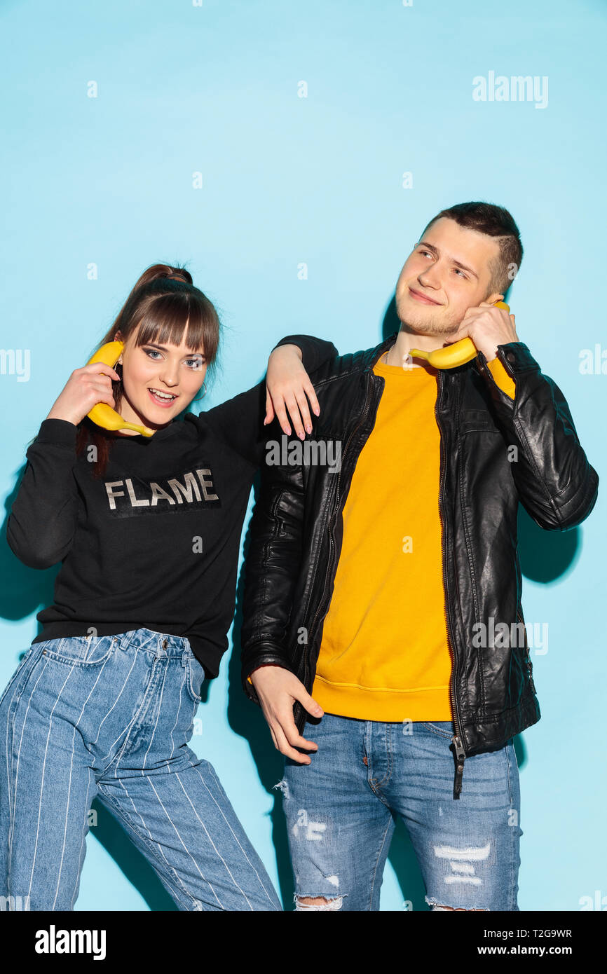Always in touch. Close up fashion portrait of two young cool hipster girl  and boy wearing jeans wear. Studio shot of two models with imaginary mobile  Stock Photo - Alamy