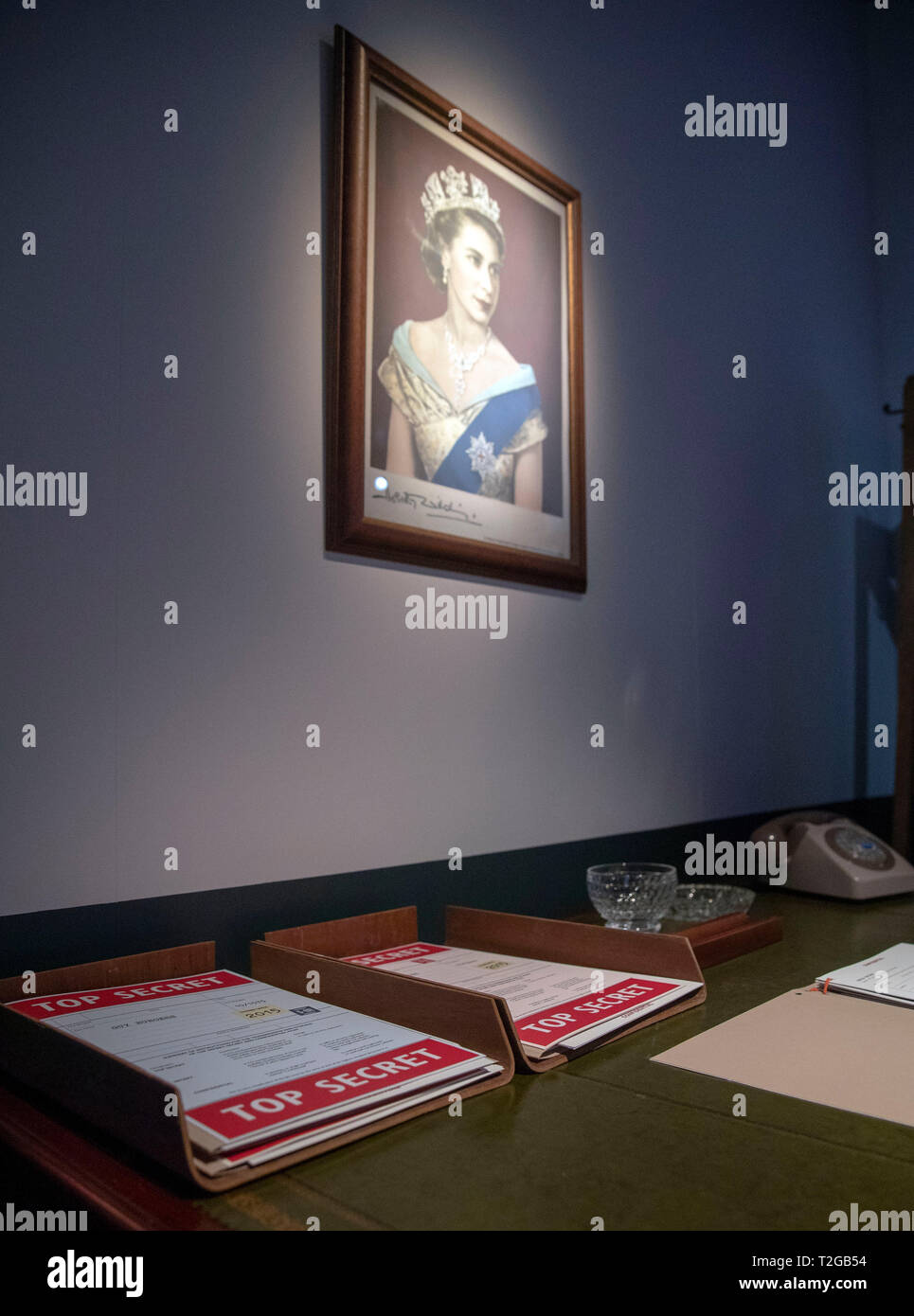 A general view of a a portrait of Queen Elizabeth II hung over a desk investigating the Cambridge Spies during the preview of the National Archives new exhibition, Protect and Survive: Britain's Cold War Revealed, at the National Archives, Richmond. Stock Photo
