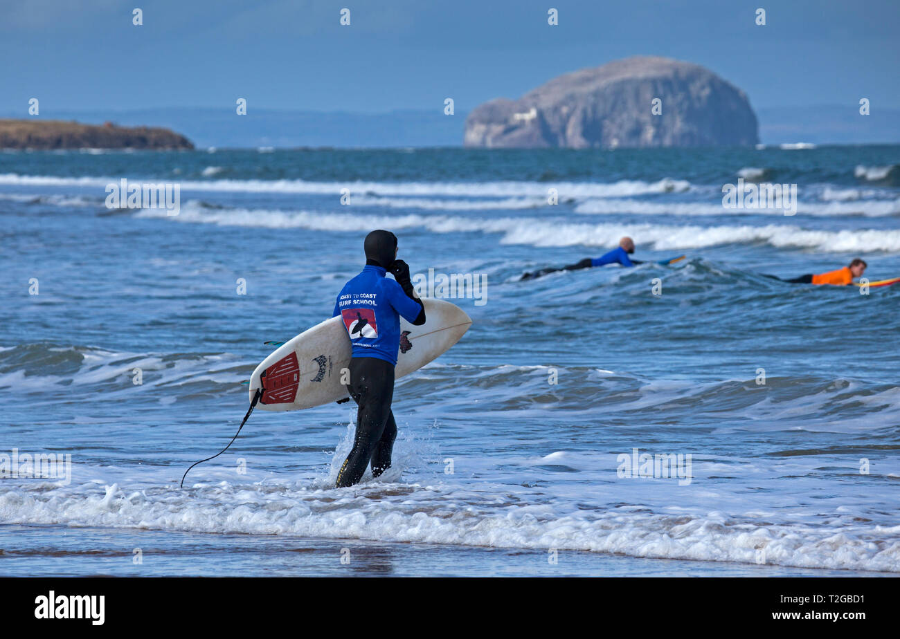 Surfers at Belhaven Bay with Bass Rock in background, Dunbar, Scotland, UK, Europe Stock Photo