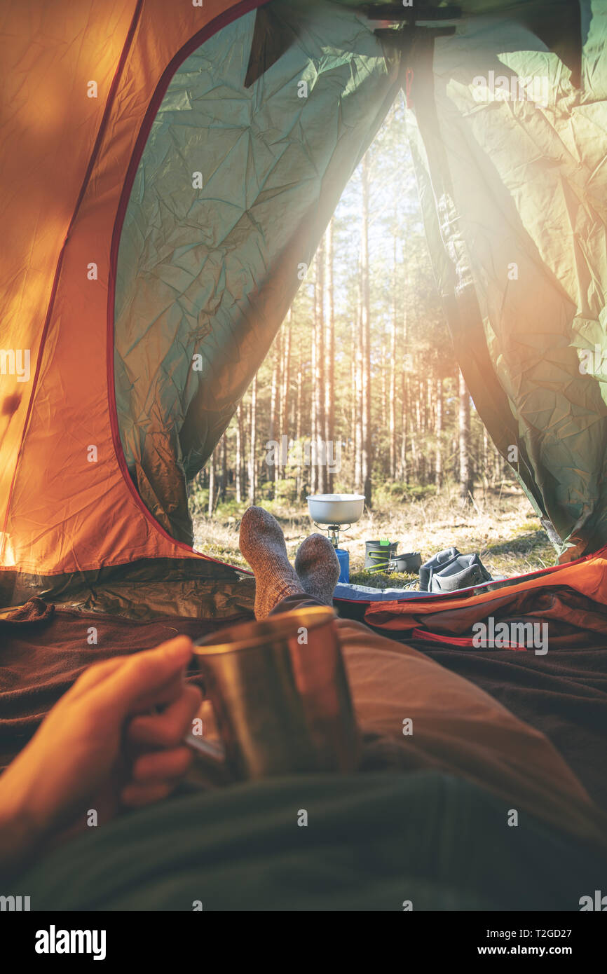 wanderlust - man relaxing in tent after hike with cup of tea Stock Photo