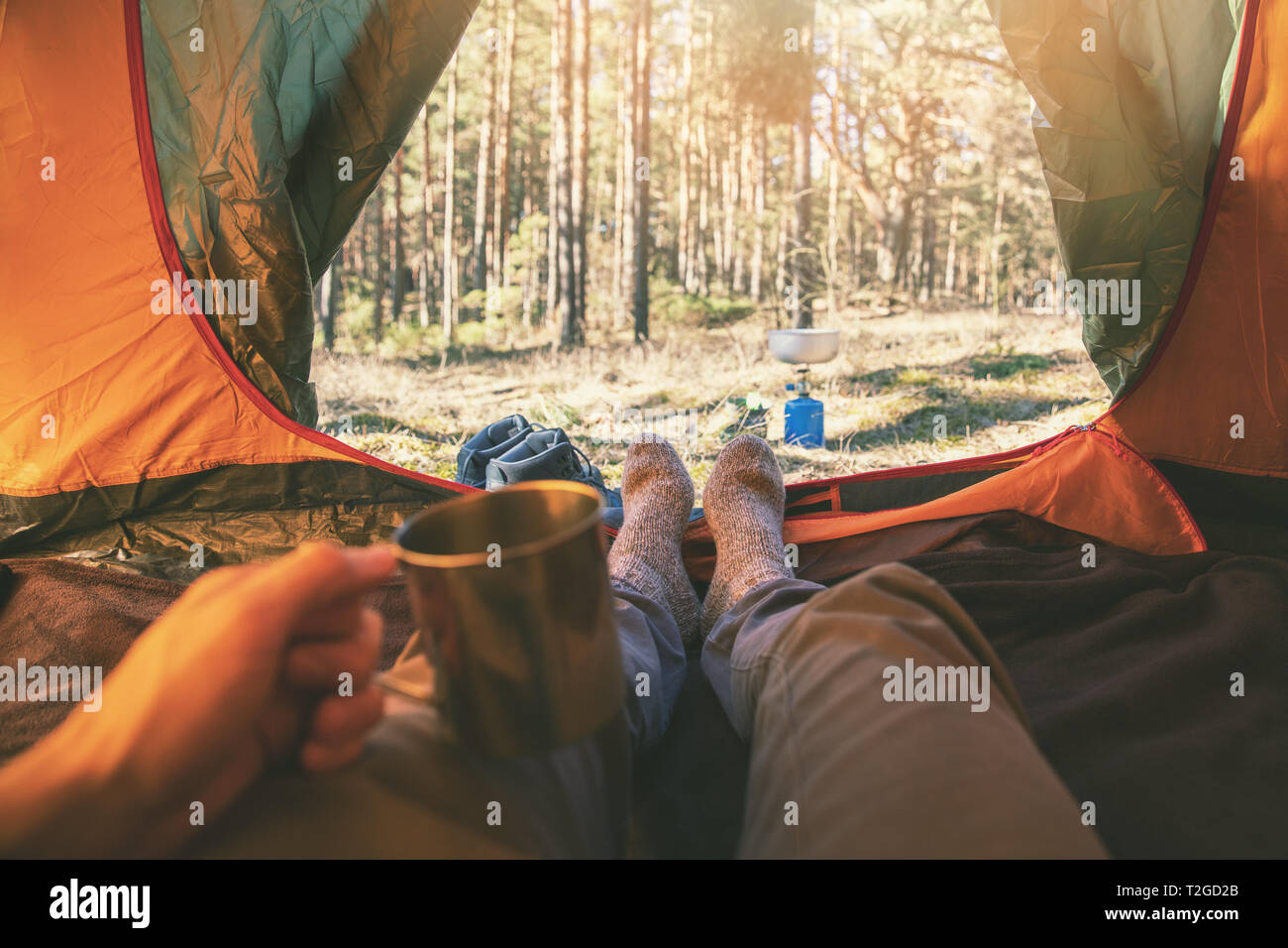 outdoor adventure tourism - man laying in tent with cup of tea Stock Photo