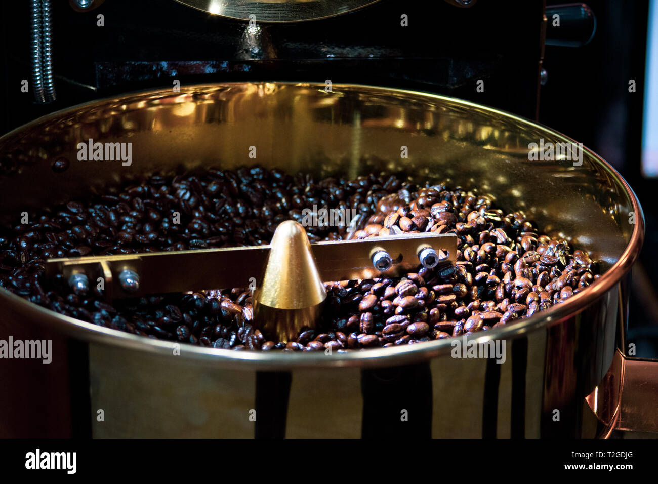 Roasted coffee in coffee roaster, Machine for roasting coffee close up ...
