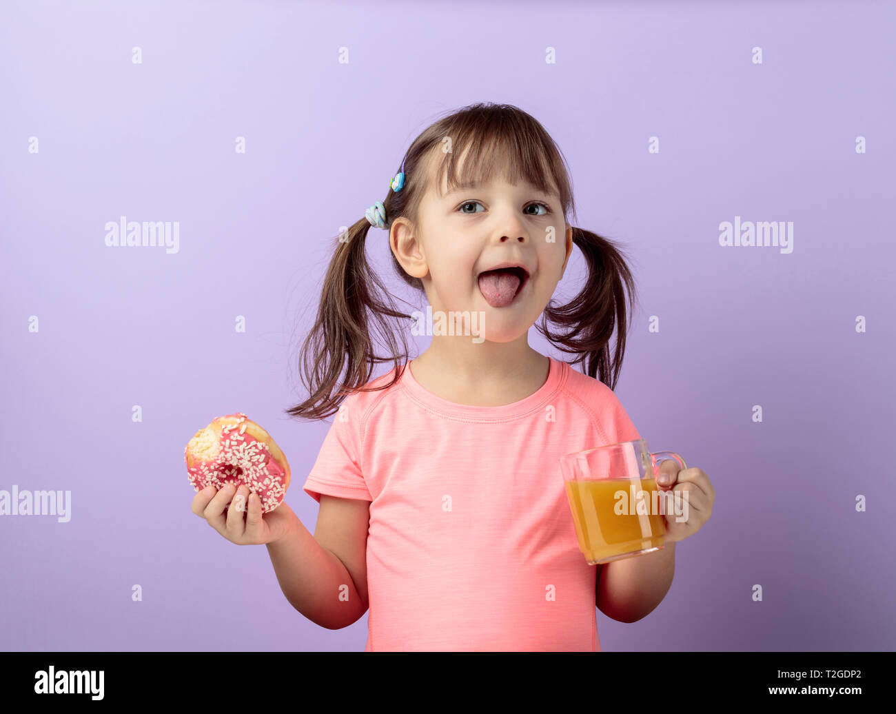 Four year old Girl In A Pink T shirt Eat Donut And Drink Juice The four-year-old-girl-in-a-pink-t-shirt-eat-donut-and-drink-juice-the