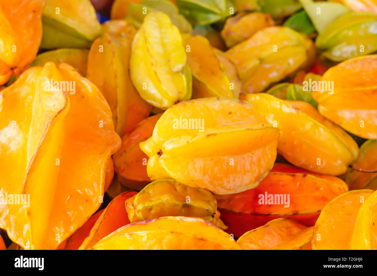 carambola fruit or fruit star for sale in market stacked with yellow orange and green tones Stock Photo