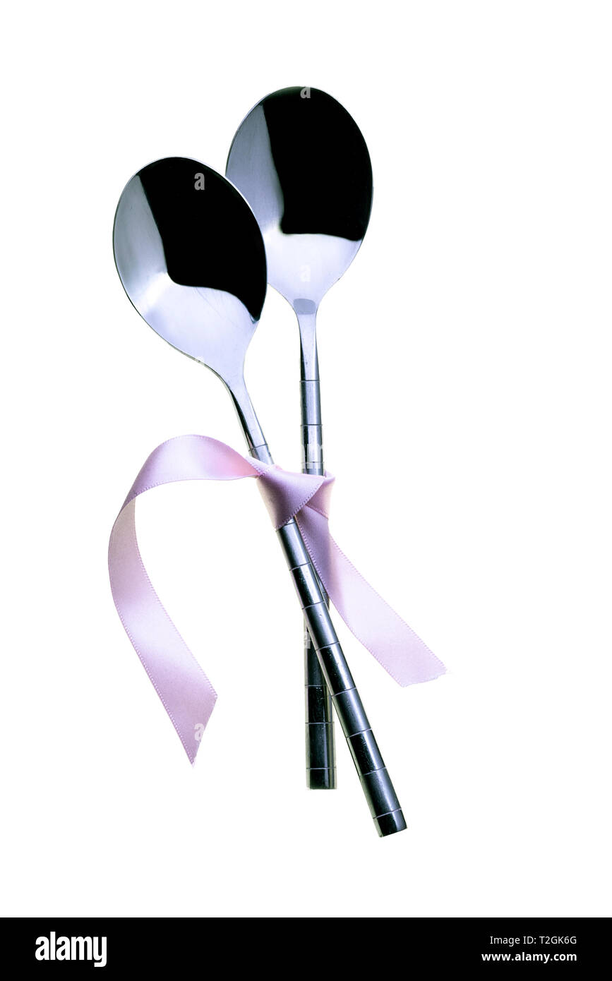Two spoons tied together with pink ribbon. On a white background Stock
