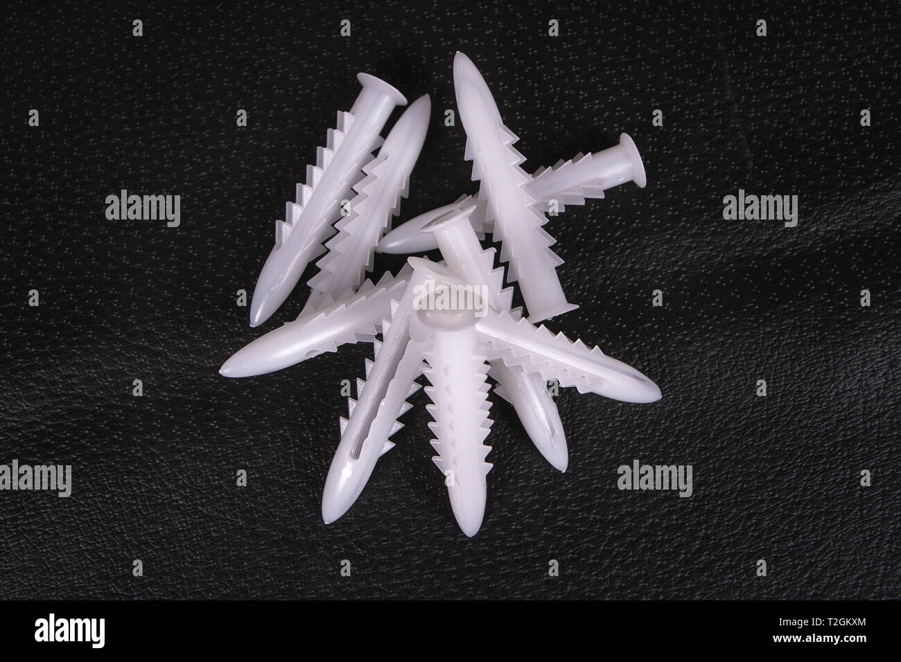 A group of plastic anchors on a black surface Stock Photo