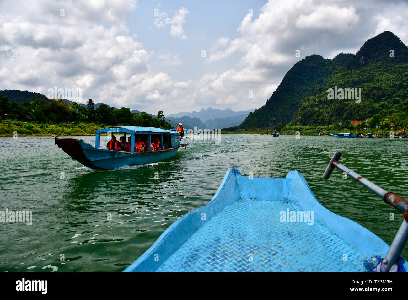 Boat ride to Phong Nha cave in Vietnam. Jungle covered limestone mountines of Phong Nha - Ke Bang National Park in the background. Stock Photo