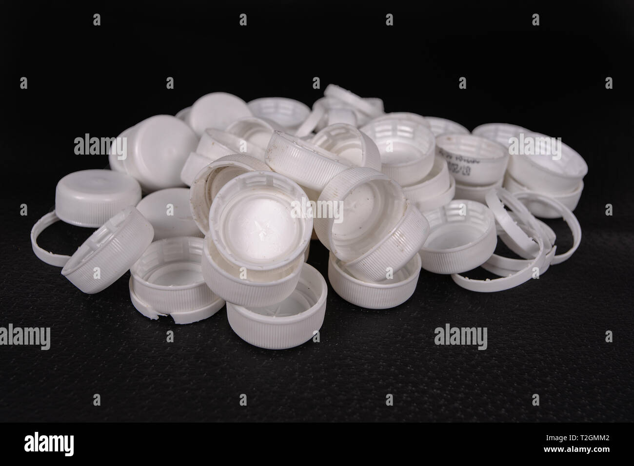 A group of used caps of plastic bottles on a black surface Stock Photo