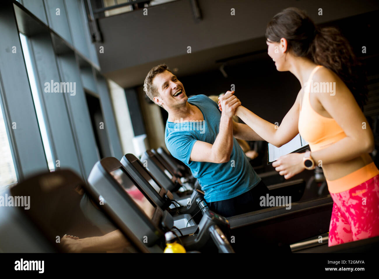 Young woman with trainer working out on treadmill in gym Stock Photo