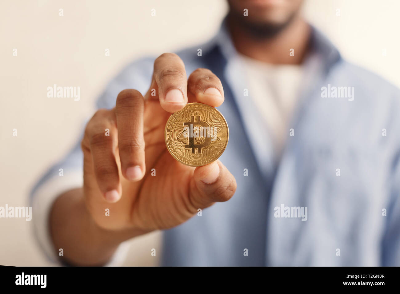 Blockchain. African-american man holding golden bitcoin in hand Stock Photo  - Alamy