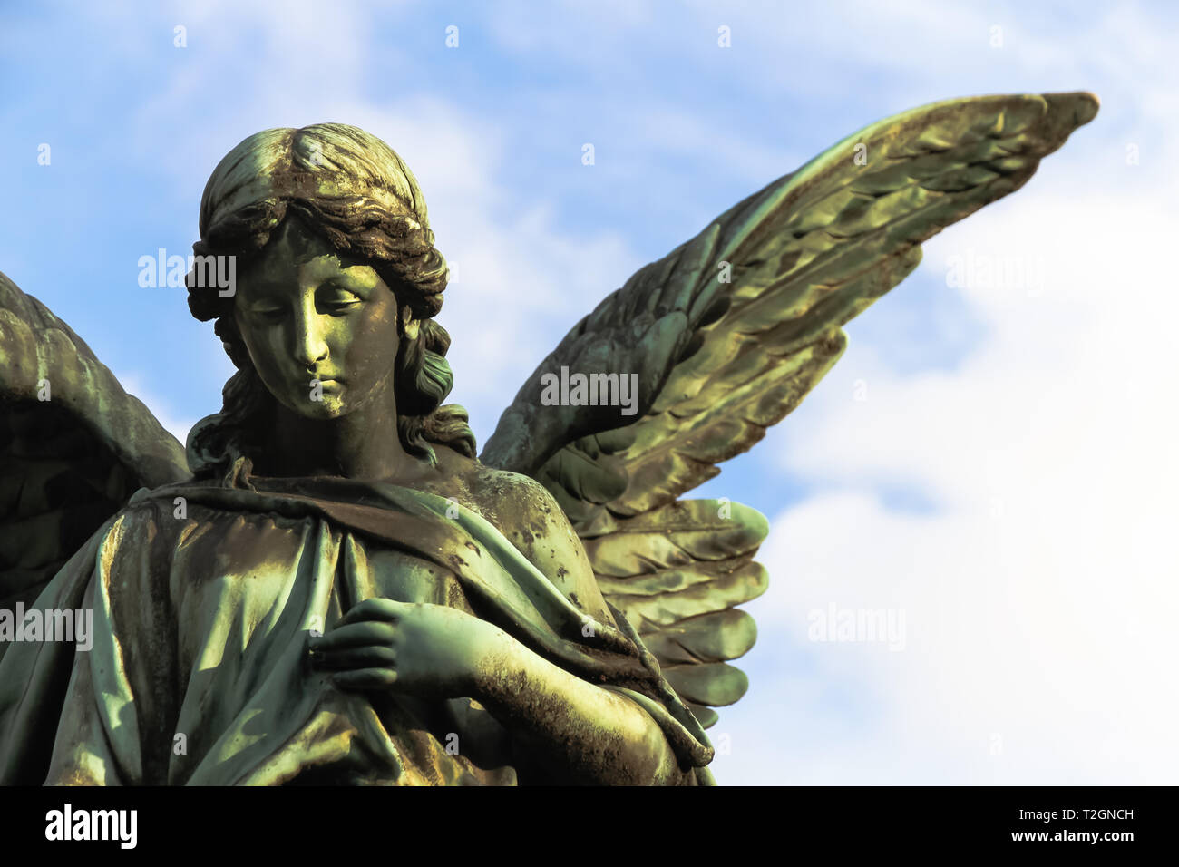 Sad angel sculpture with open long wings across the frame Sad angel sculpture with open long wings across the frame