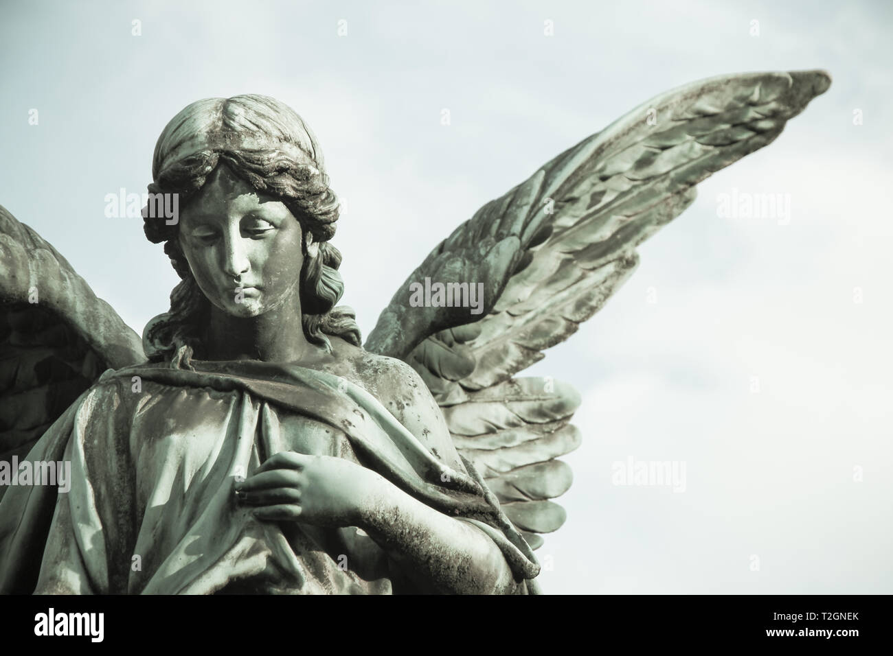 Sad angel sculpture with open long wings across the frame Sad angel sculpture with open long wings across the frame