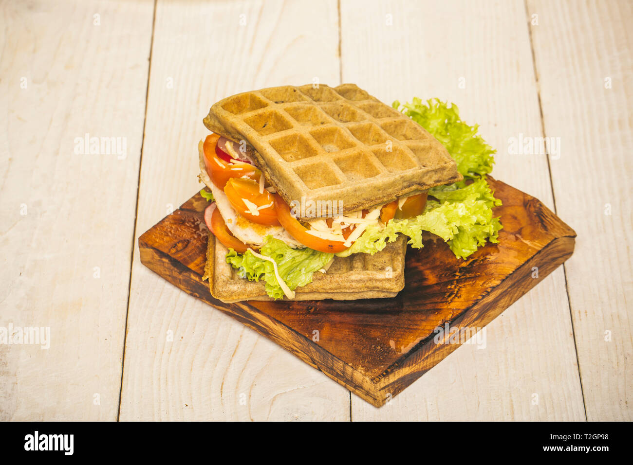 Food, snack, meal. Waffles sandwich with chicken, vegetables and cheese on wooden background. Diet, healthy dieting, health. Cuisine, menu recipes Waf Stock Photo