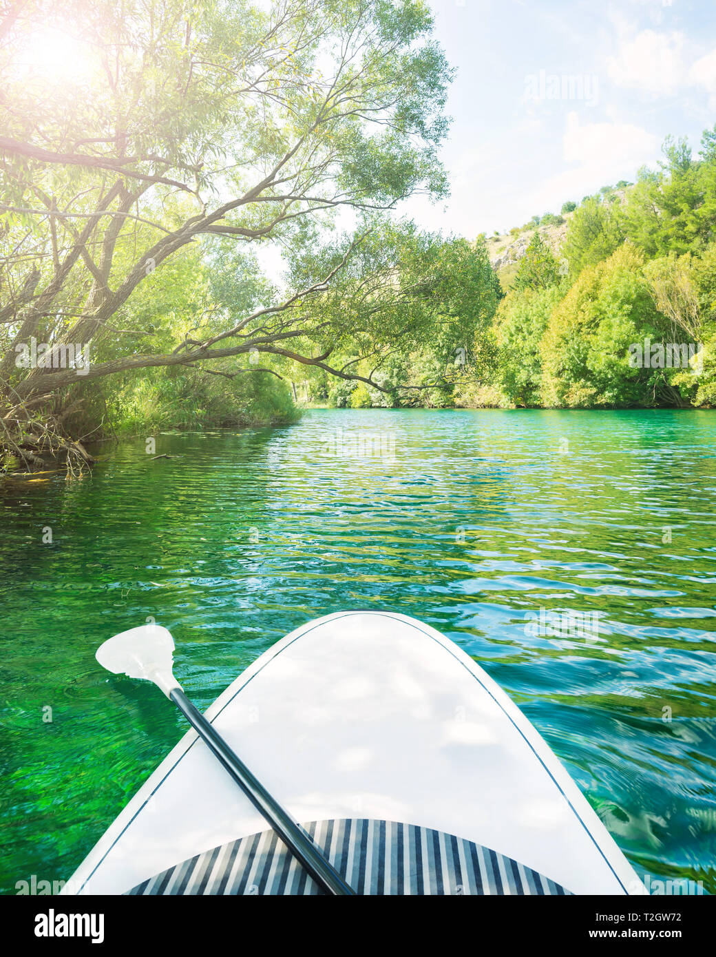 white stand up paddle board without person floating down beautiful river with clear turquoise water on sunny summer day, Zrmanja, Dalmatia, Croatia Stock Photo