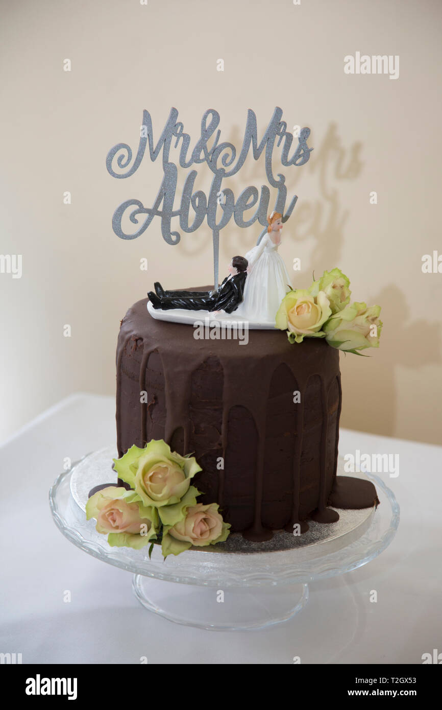 Chocolate wedding cake with funny cake topper of Bride dragging groom along  by his collar Stock Photo - Alamy