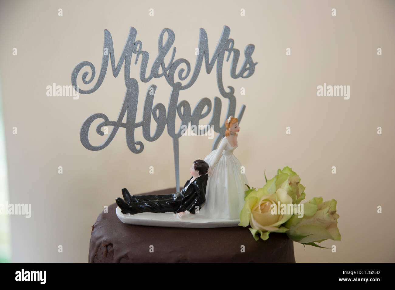 Chocolate wedding cake with funny cake topper of Bride dragging groom along  by his collar Stock Photo - Alamy