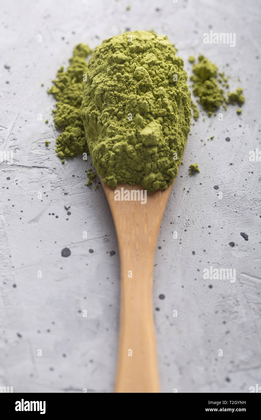 Top view of green tea matcha in a spoon on concrete surface. It is a rich source of antioxidants and polyphenols. When preparing, the powder is partia Stock Photo