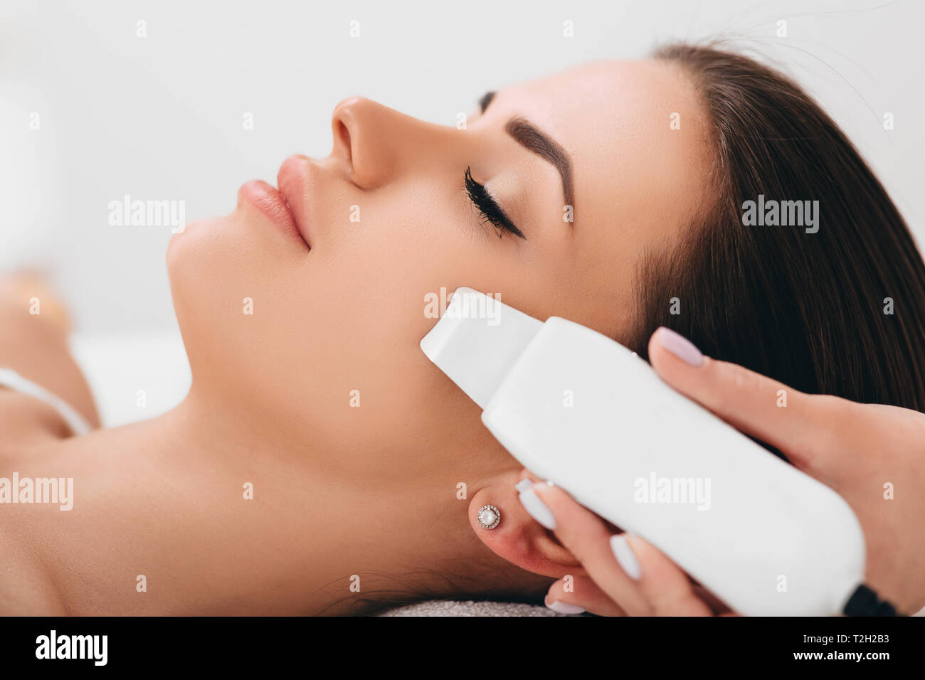 Beautiful woman receiving ultrasonic facial exfoliation at spa. Procedure clearing clogged pores, ultrasonic treatment for skin rejuvenation Stock Photo