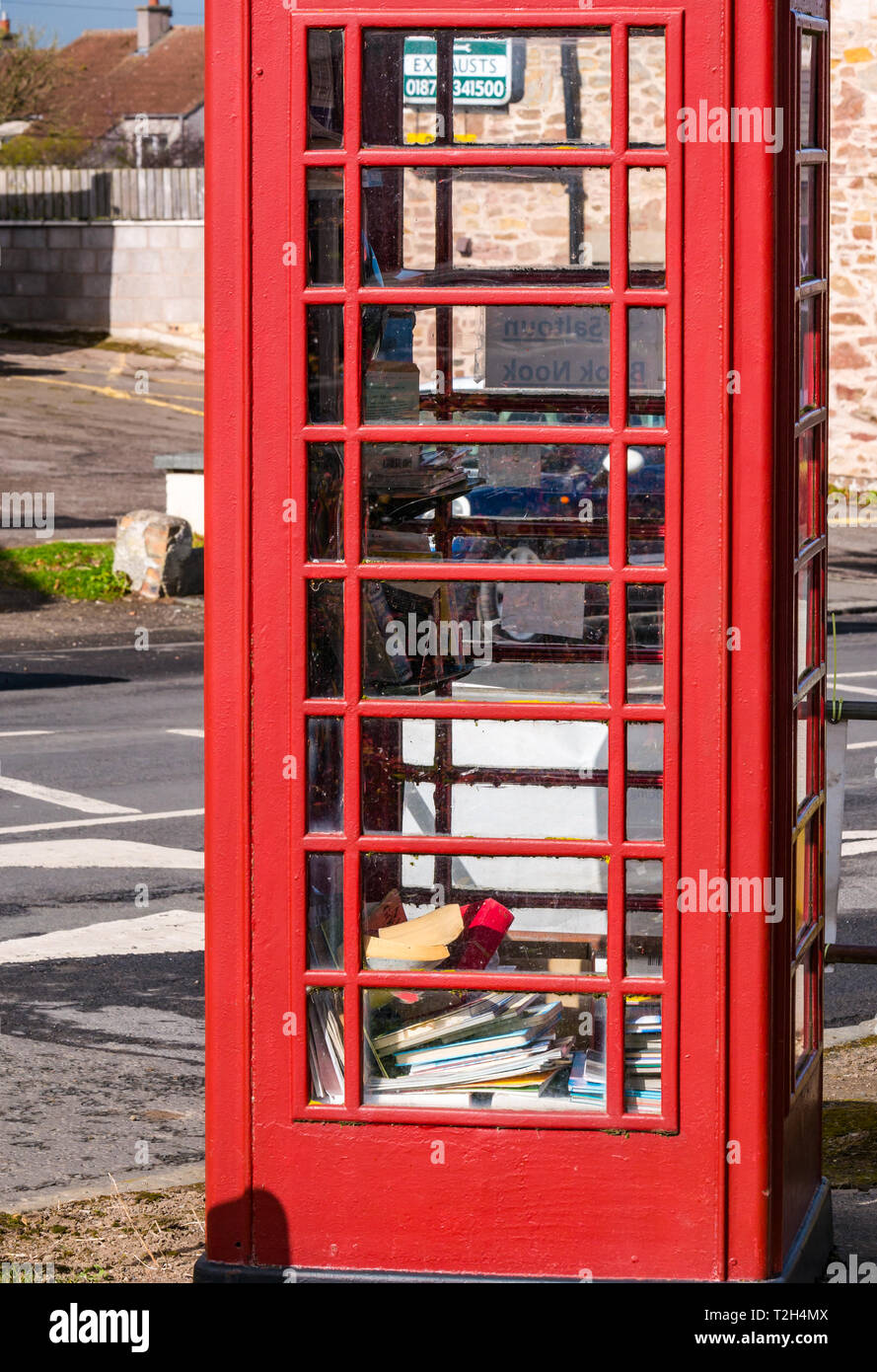 Old red telephone box converted to book lending library in conservation village, East Saltoun, East Lothian, Scotland, UK Stock Photo