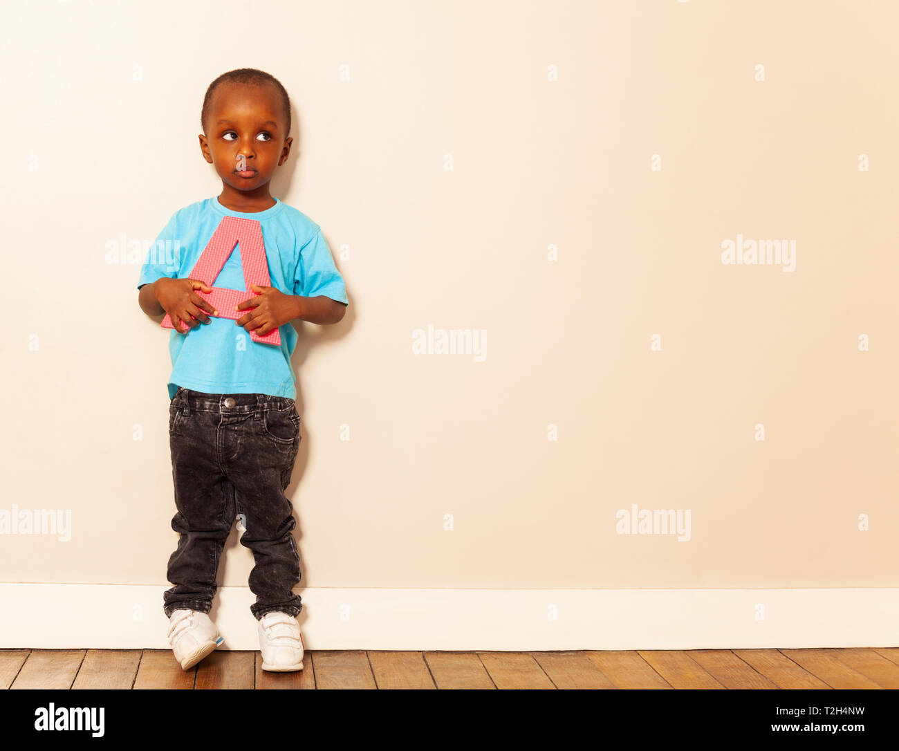 Little black boy hold a letter with calm expression standing over white wall Stock Photo