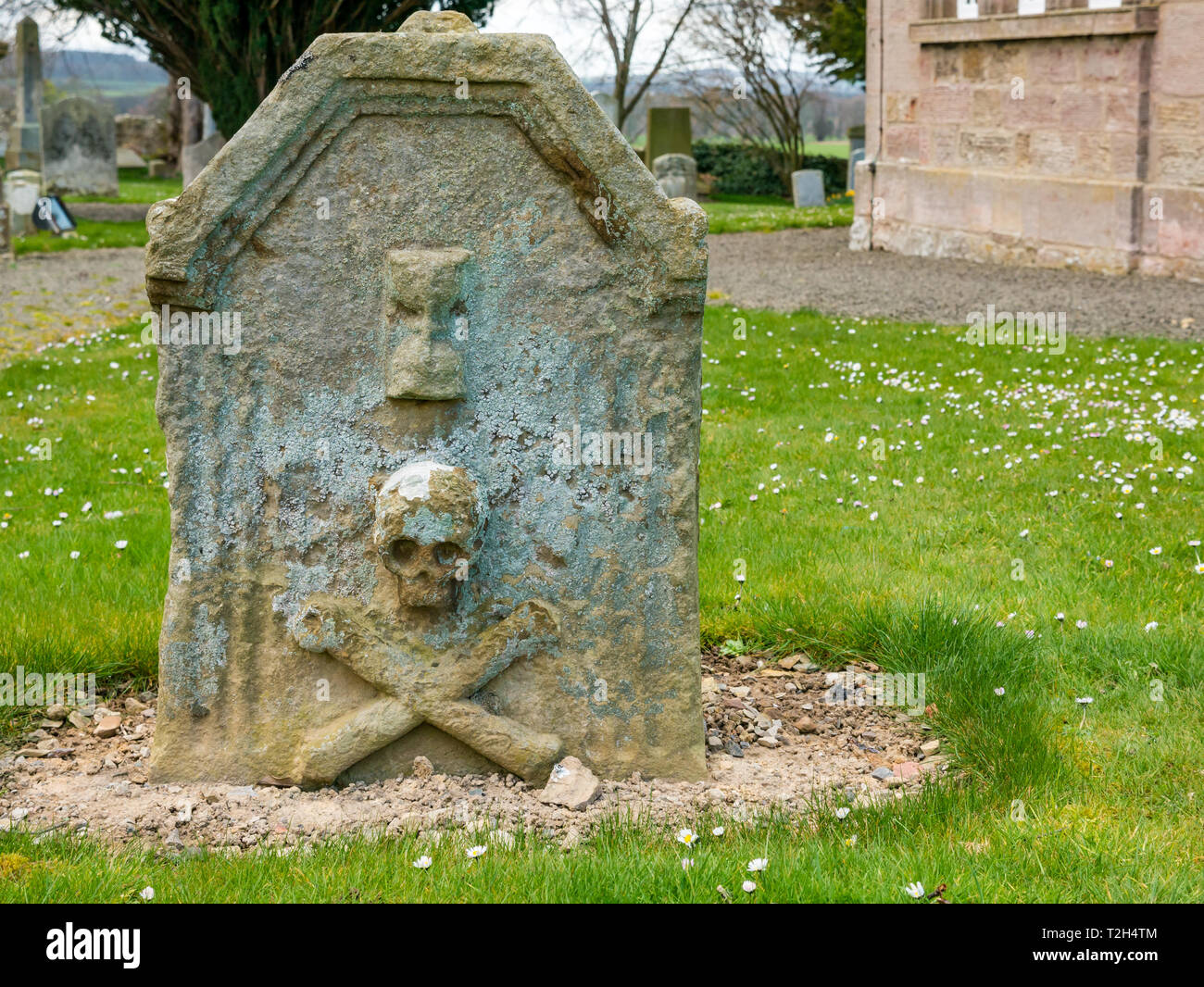 Old worn skull and crossbones on gravestone in village churchyard,, East Saltoun, East Lothian, Scotland, UK Stock Photo