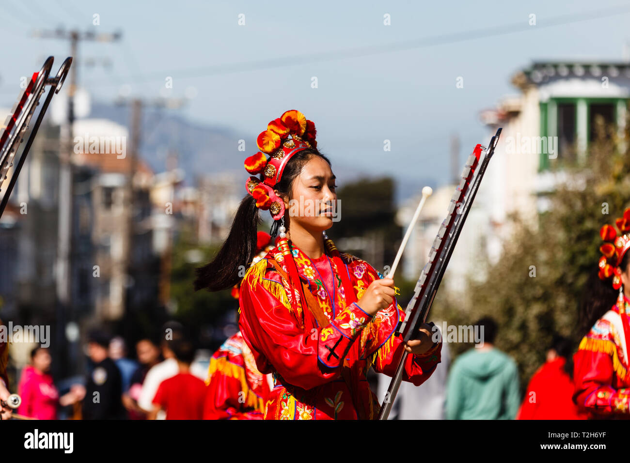Closeup of Chinese girl in traditional red costume playing xylophone in