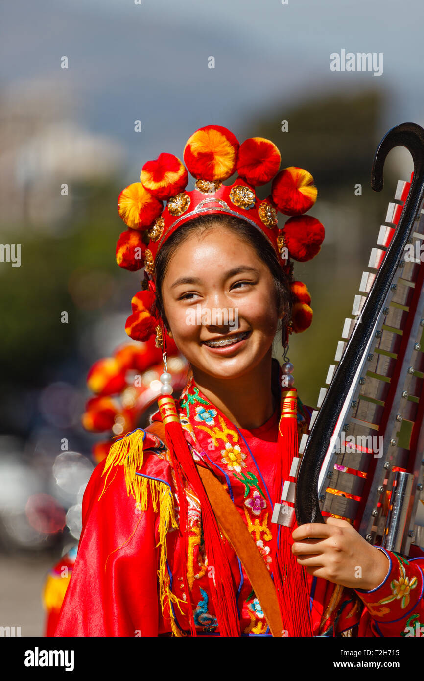 Chinese girl in traditional red costume smiling with her xylophone in
