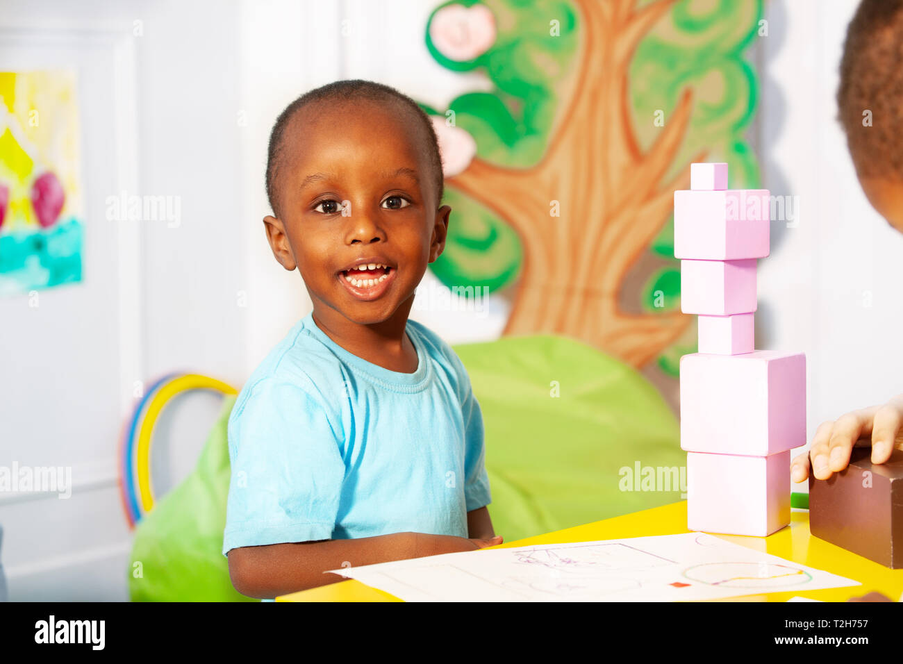 Portrait of one little black boy building blocks in nursery class school on  the table with big smile and curly hair Stock Photo - Alamy