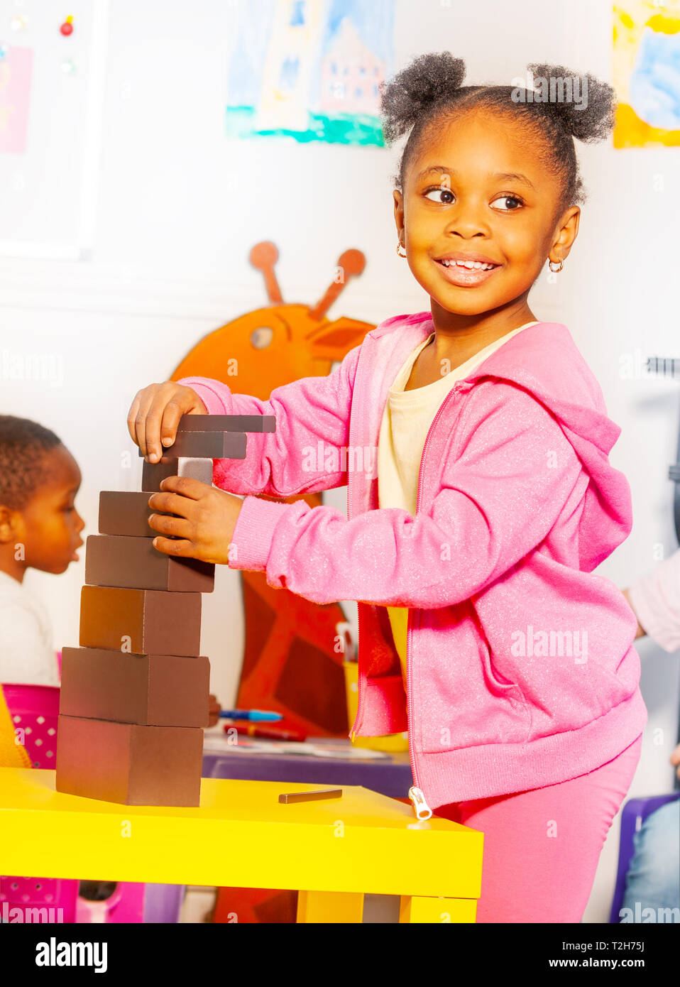 Portrait of one little black girl building blocks in nursery class school  on the table with big smile and curly hair Stock Photo - Alamy