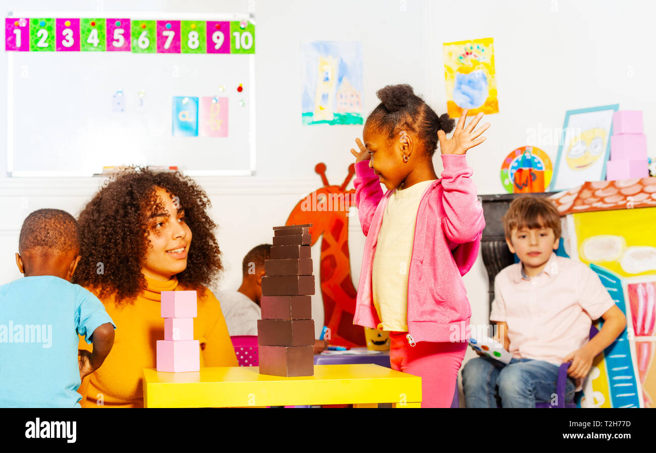 Little Black Girl Curly Hair Play Blocks With Teacher In Nursery