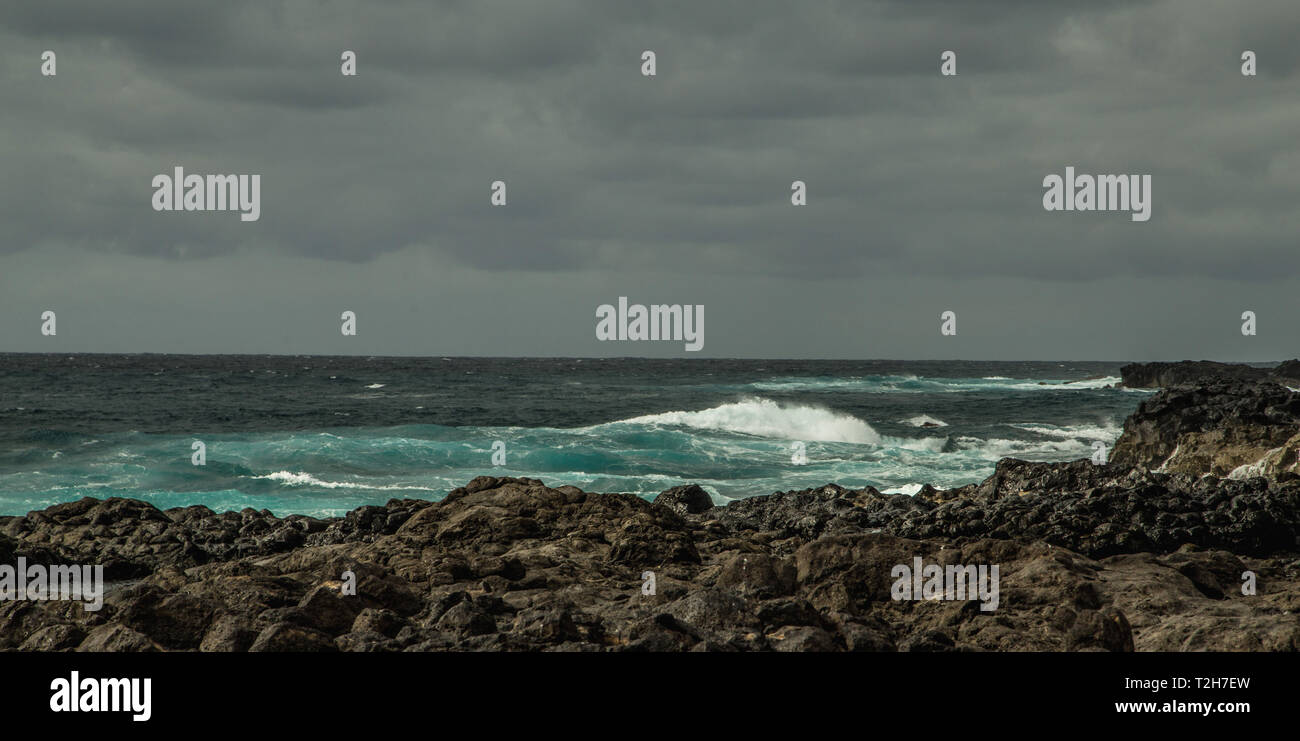 stony bank, ocean at the day. grey sky and small waves, lanzarote island Stock Photo