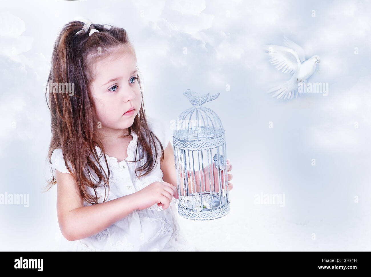 The little girl keeps letting the bird out of the cage. Easter Stock Photo