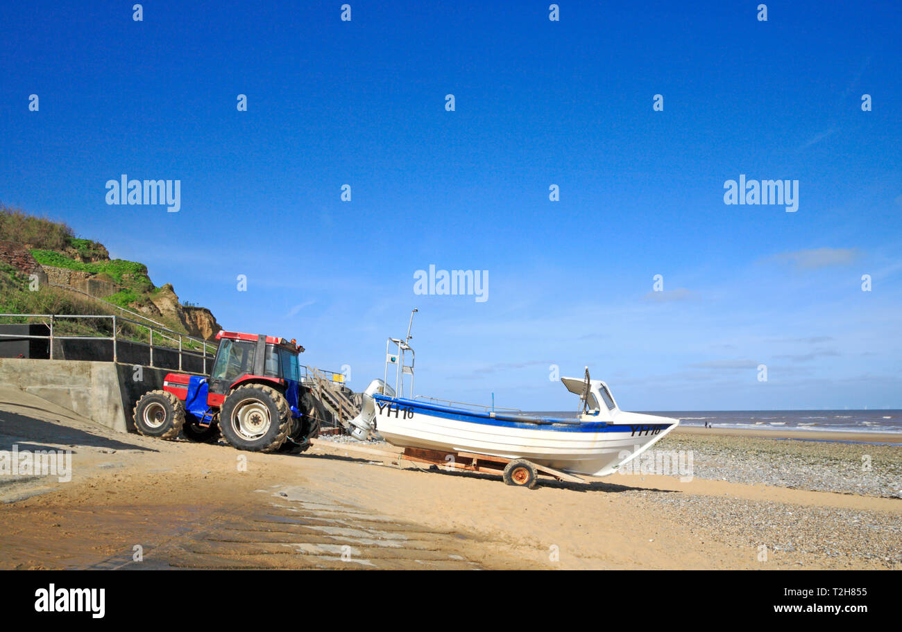 A fishing boat and tractor by the seawall on the North Norfolk beach at