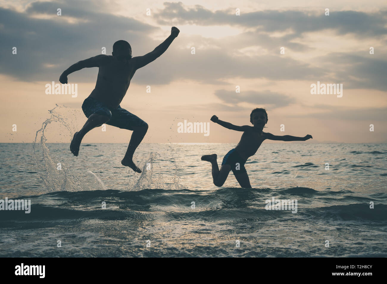 Father and son playing on the beach at the sunset time. People having fun outdoors.  Concept of happy vacation and friendly family. Stock Photo