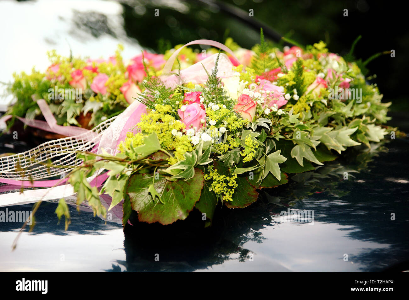 A flower bouquet for the wedding on the hood of a car. Stock Photo