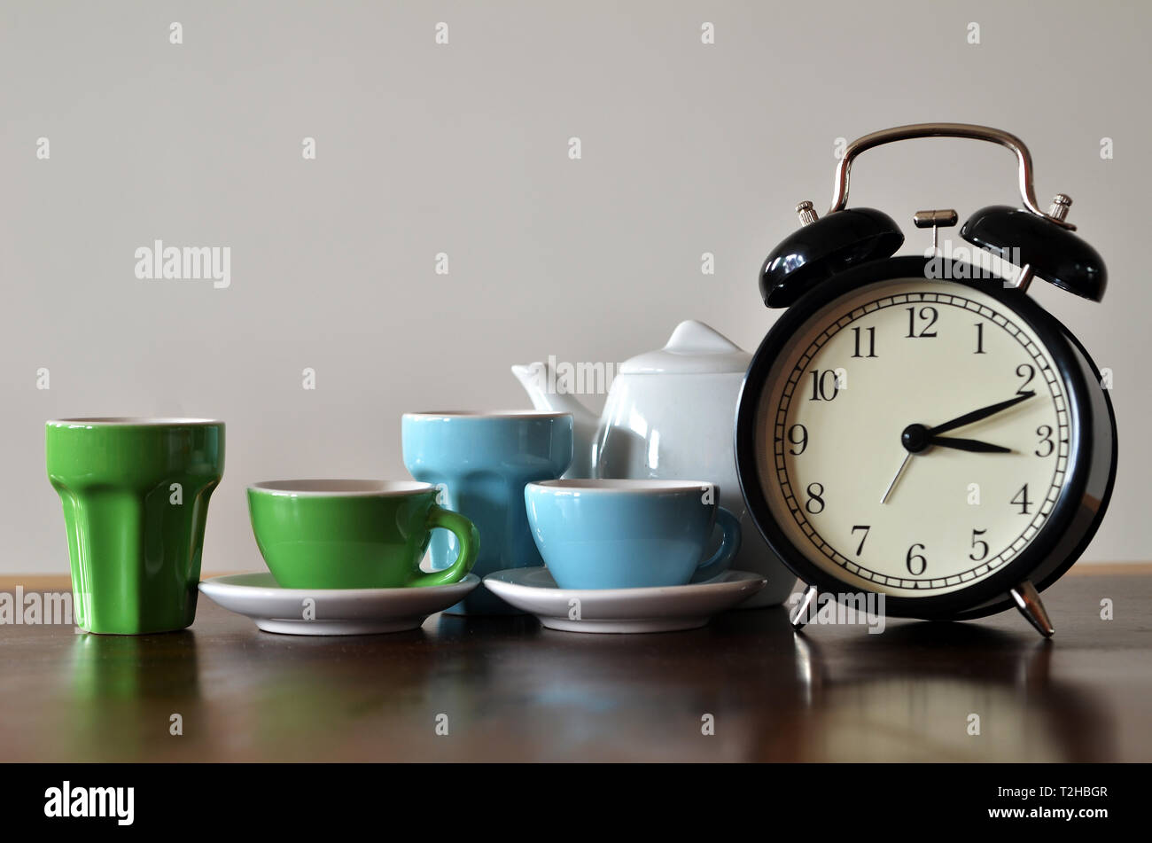 Vintage alarm clock with colorful tea set Stock Photo Alamy