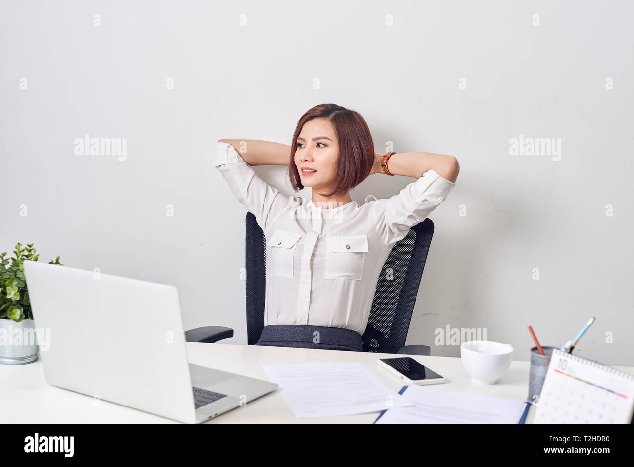 Business woman resting in the office after a working day leaning back her hands behind her head Stock Photo