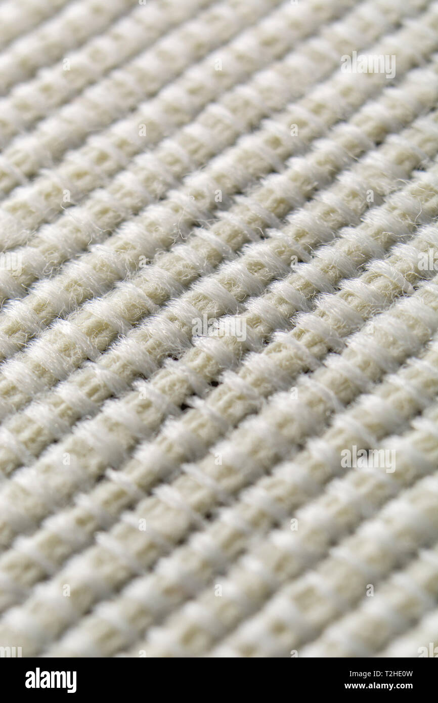 Close-up / extreme macro shot of pale polyester material used for a table runner. Stitched line, line of stitches, thread pattern. Stock Photo
