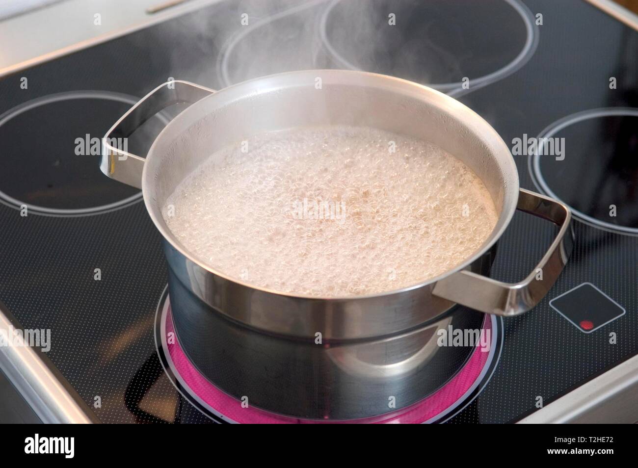 Boiling steaming water in pot on stove with ceramic hob hires stock