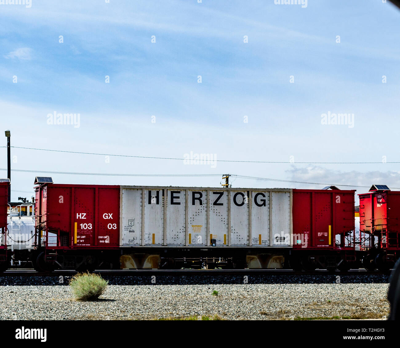 A Herzog Railroad Services hopper car in a train in Mojave California