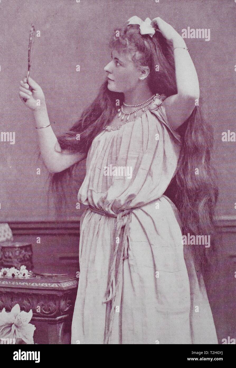 Girl with very long hair looks in a hand mirror, 1895, historical illustration, Germany Stock Photo