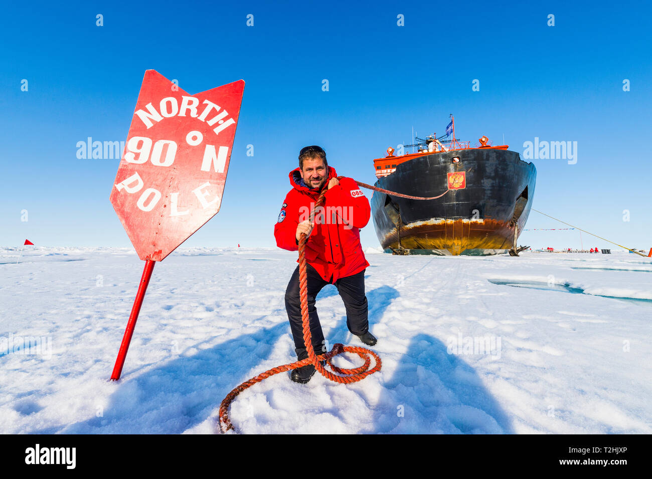 Man pretending to pull the Icebreaker '50 years of victory' on the North Pole, Arctic Stock Photo