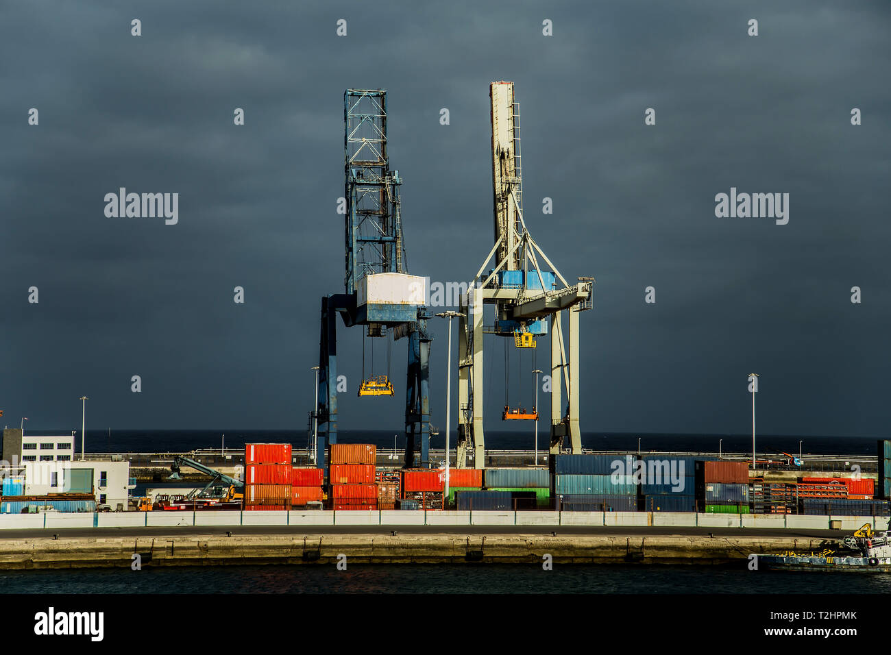 cranes and colored containers in the port of ocean. the sky is grey. Stock Photo