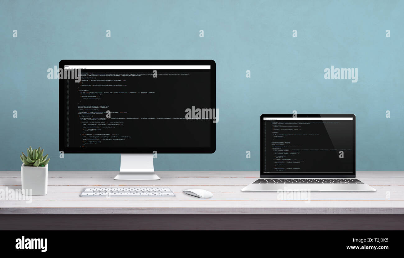 Desktop computer and laptop on work desk with programming editor on display. Concept of programming studio. Stock Photo