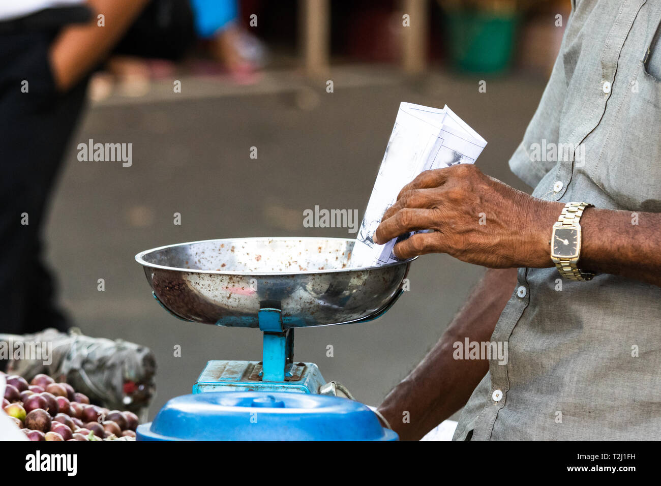 A sri lankan man hand, weighing dry fruits on a scale at a street